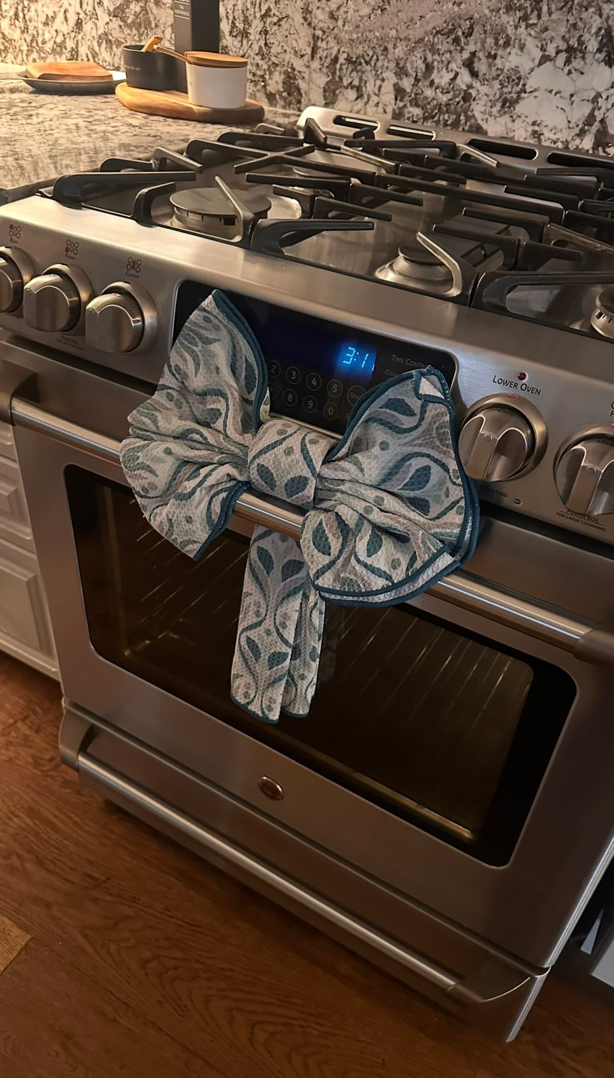 Blue patterned kitchen towel tied in a large bow on a stainless steel oven door handle.